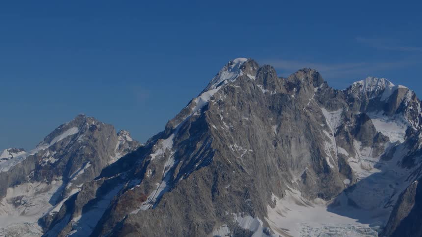 A panoramic and static view of the majestic, snow-dusted Alps against a vibrant blue sky