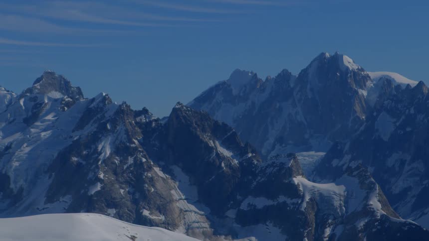 A stunning aerial view pulls back to reveal the majestic, snow-covered peaks of the Alps on a clear day