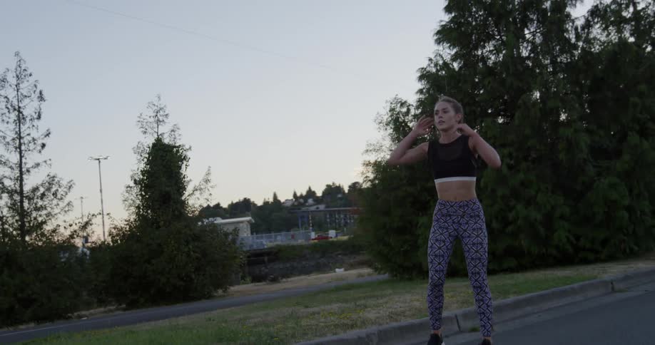 A jogging woman slows and stops to rest with hands on her knees