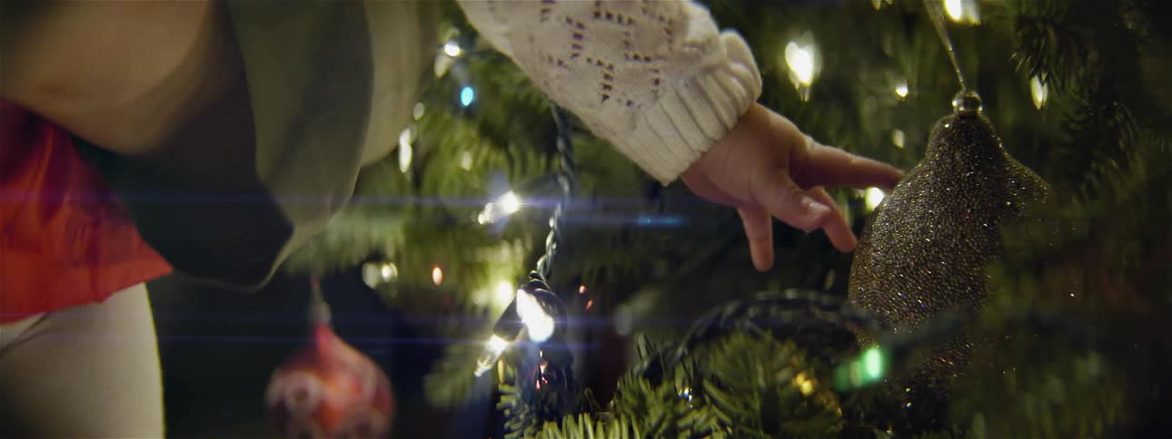 A person is touching the ornaments on a tree