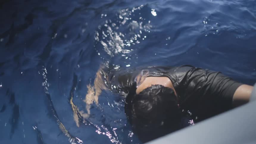 A man wearing a snorkel and mask treads water in the deep blue ocean in slow motion