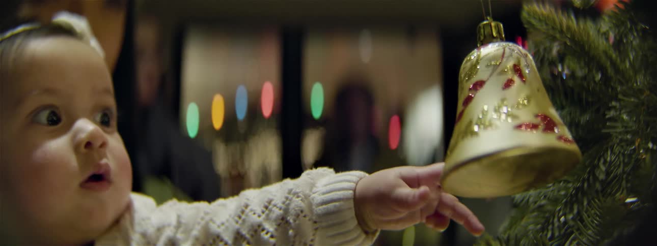 A baby is pushing an ornament on a tree