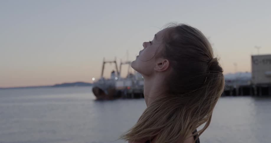 A woman looks out over the water then up
