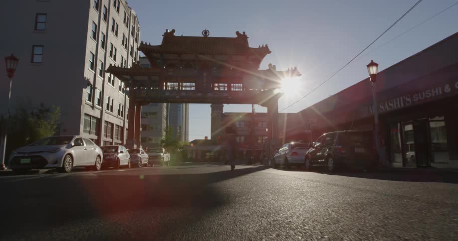 A woman jogs on a city street as the sun shines overhead