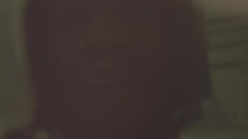 A gritty and disorienting close-up of a man's face reflected in a dark, moving environment