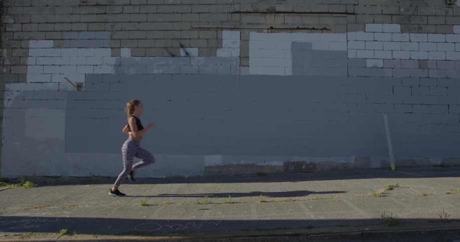 Woman runs down a city street next to an old brick building