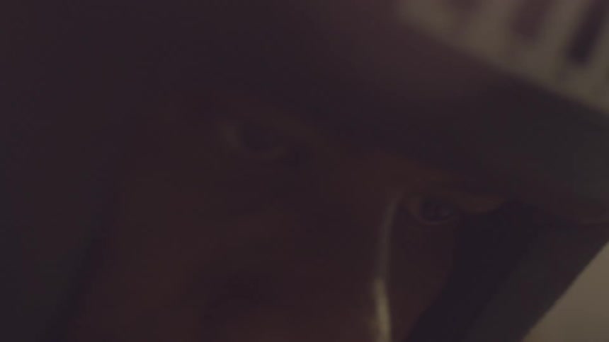 A blurry, shaky, and intimate close-up of a person's face moving in the dark