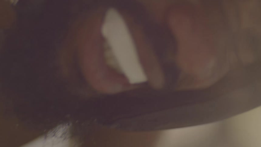 Extreme close-up shot of a man shaving his chin stubble with an electric razor in slow motion