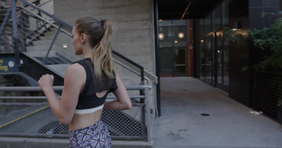 Woman jogs on a bridge in a city