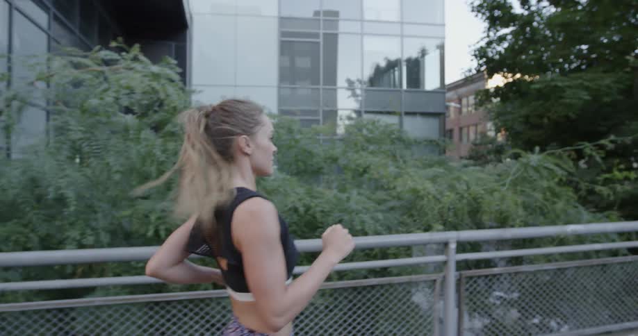 A woman jogs over a pedestrian overpass in a city