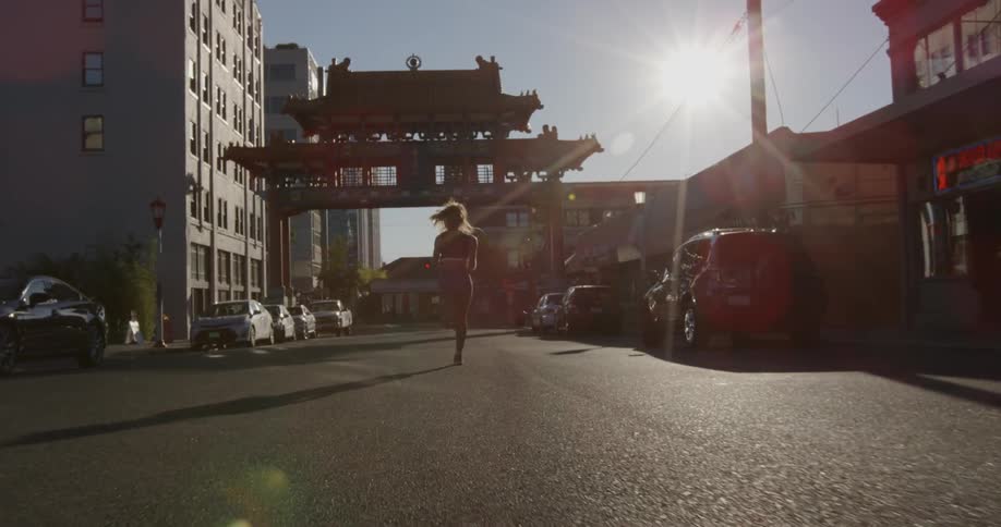 Woman jogs down a car lined street in the city