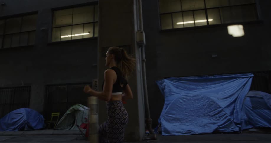A woman jogs by a city building at night