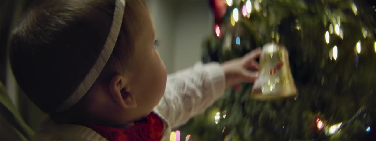 An infant reaches to touch christmas ornaments