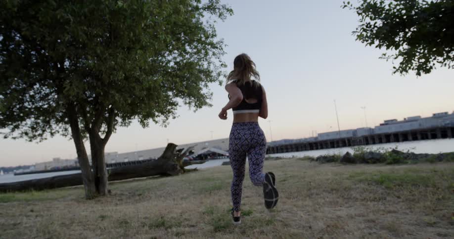 A female jogger runs toward a harbor at dusk