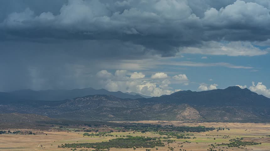 Dramatic timelapse captures a summer monsoon storm with dark clouds and rain sweeping across a vast mountain valley