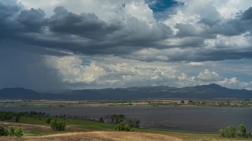 Timelapse of a powerful storm system with dark, churning clouds moving over a large lake and distant mountains