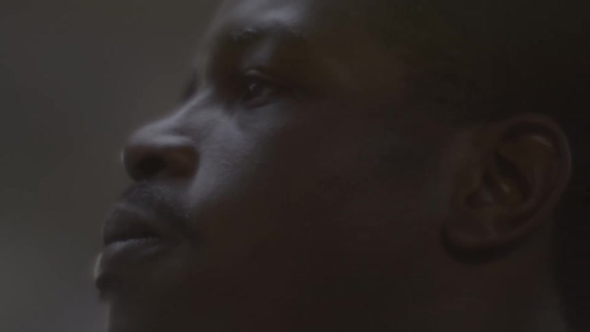 An intense and dramatic close-up of a young man's profile as he contemplates in a dimly lit room