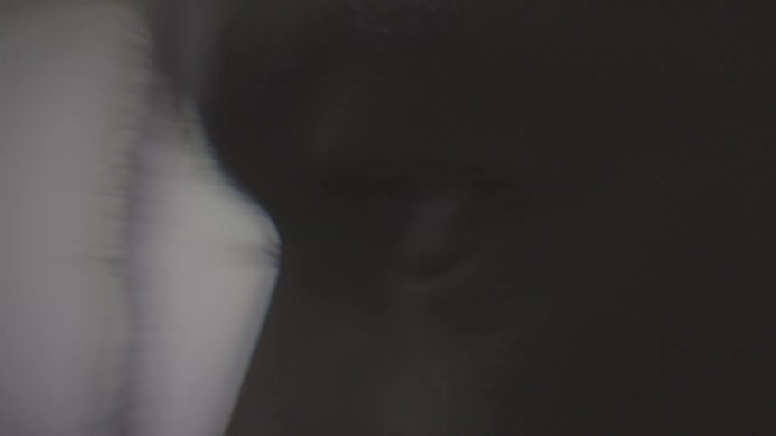 A slow motion, extreme close-up of a Black person's eye blinking in the dark
