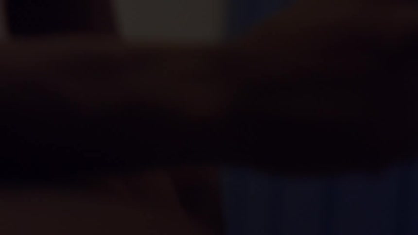 An athlete warms up their hands and grabs a yellow resistance band in a dimly lit locker room