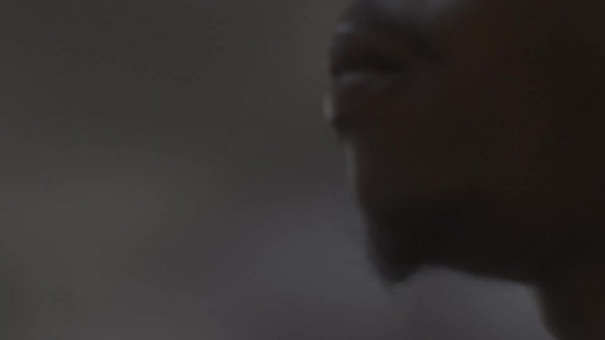 A close-up profile shot of an athlete's face in low light as he intensely chews on his mouthguard