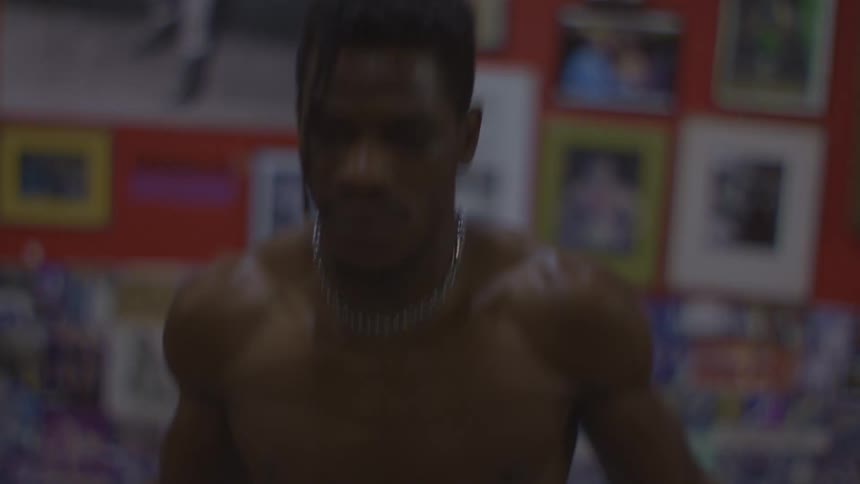 Dramatic close-up of a shirtless boxer intensely jumping rope in a gritty, old-school gym