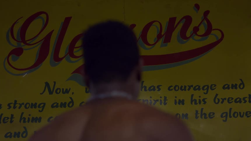 Close up of a boxer's back as he contemplates the iconic Gleason's Gym sign in Brooklyn