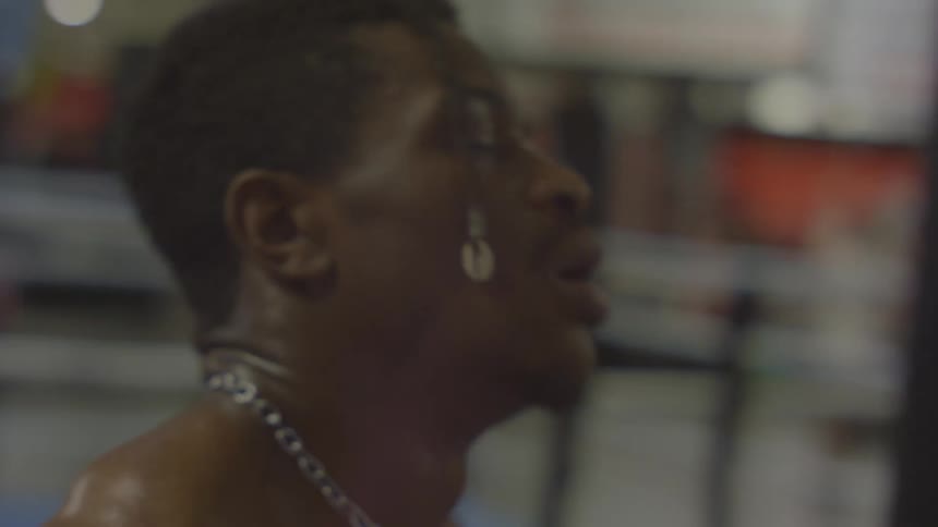 Close-up slow motion shot of an exhausted and sweaty boxer catching his breath while leaning on a heavy bag