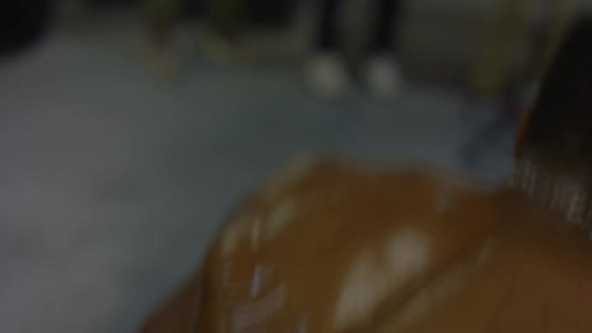 A close-up slow-motion shot from behind captures the flexing, sweaty back muscles of a boxer training on a speed bag