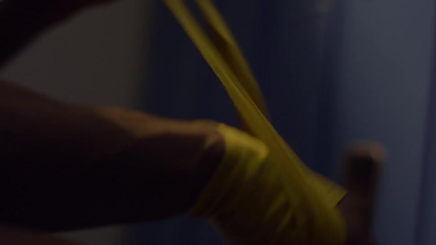 A close up of a fighter meticulously wrapping their hands in a dark locker room in slow motion