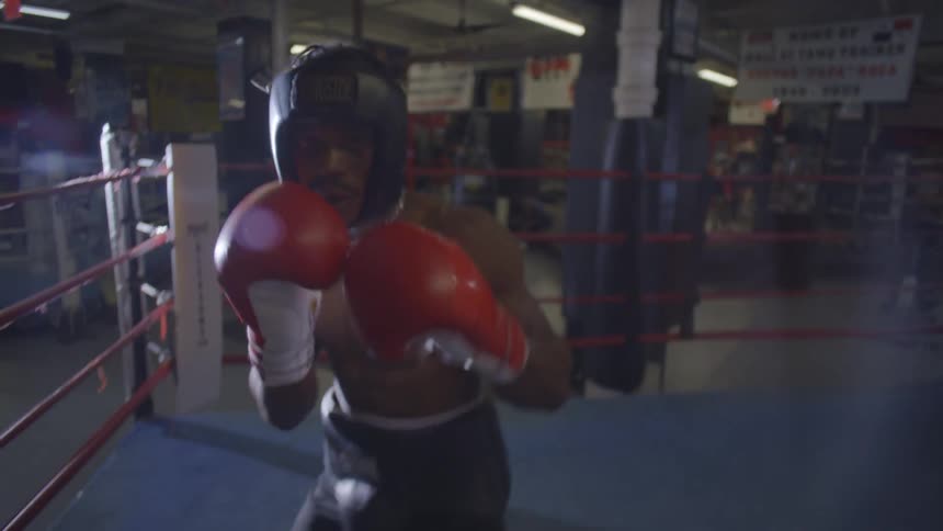 A boxer throws intense punches towards the camera in a first-person perspective sparring session inside a gym's boxing ring