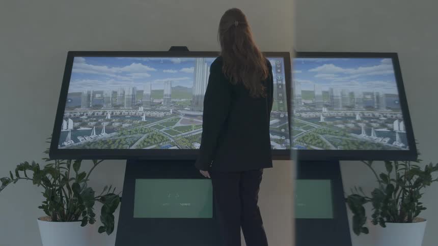 A female architect uses a large interactive touchscreen to explore a 3D model of a futuristic coastal city development