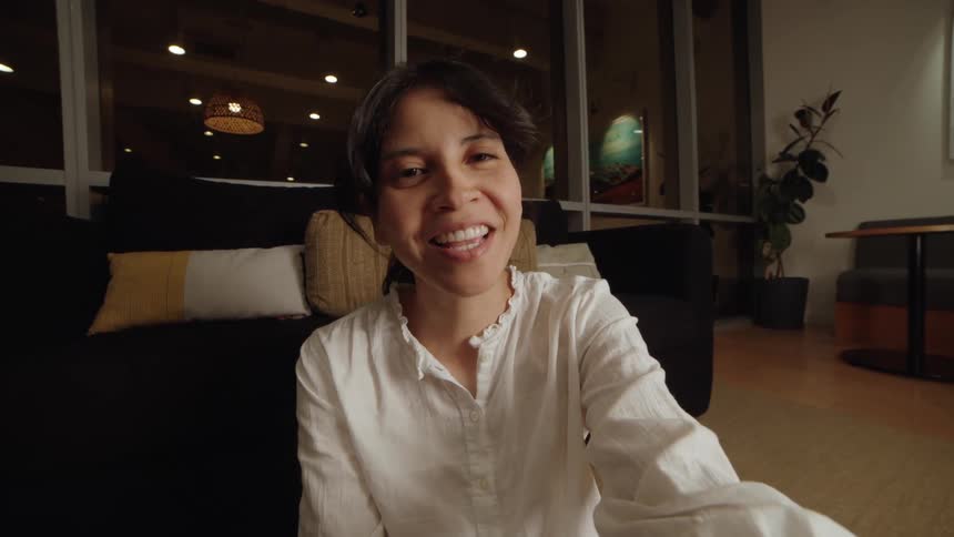 A happy woman laughs and then gets into a surprising conversation during a video call at home