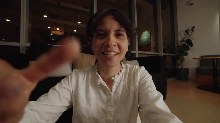 A woman's point of view on a video call, reaching for the screen as she smiles and reacts to the conversation at night