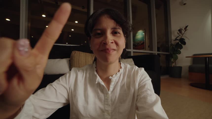 A point-of-view shot of a smiling woman using her finger to swipe and scroll on an unseen digital device at night