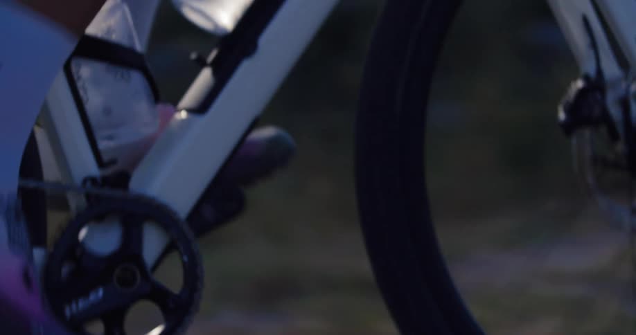 A soft focus, slow-motion close-up of a cyclist pedaling their bike during an evening ride