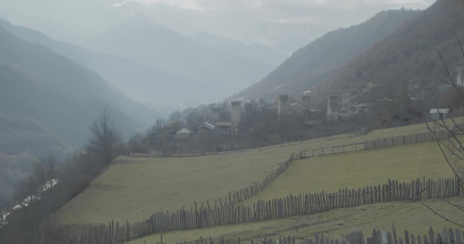 A static shot of an ancient village with stone Svan towers nestled in a foggy mountain valley in Georgia