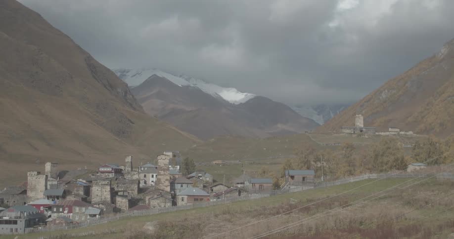 A slow zoom out reveals the ancient stone village of Ushguli in Georgia, nestled in a vast mountain valley beneath snow-capped peaks
