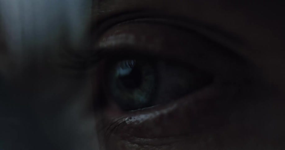 An extreme close-up macro shot of a blue eye opening slowly and dramatically in the darkness