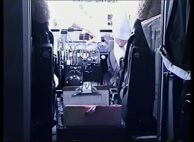 Vintage VHS footage slowly zooms into an airplane cockpit where two pilots are seated at the instrument panel controls