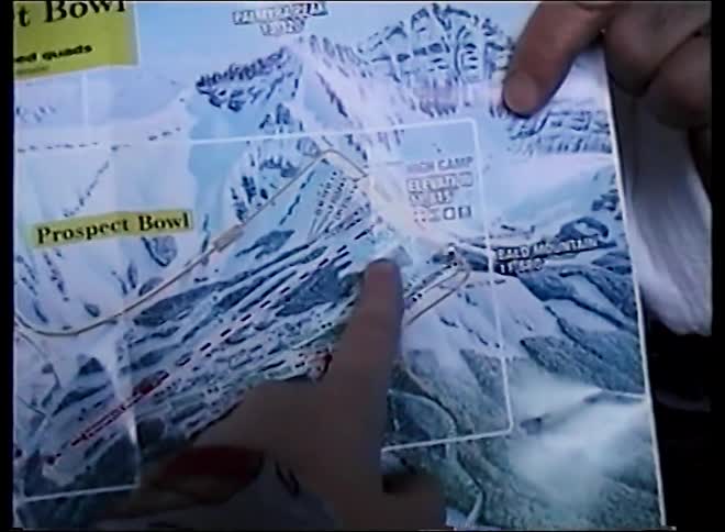 A close-up of two people pointing at locations on a ski resort trail map while planning their route