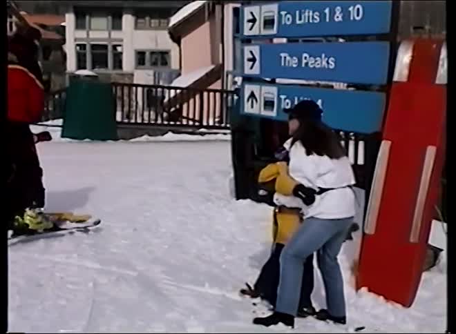 A mother gives her young child a big hug while they are learning to ski at a winter resort