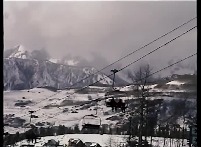 A gondola passes by, unveiling a scenic, snow-covered mountain valley with chairlifts at a ski resort