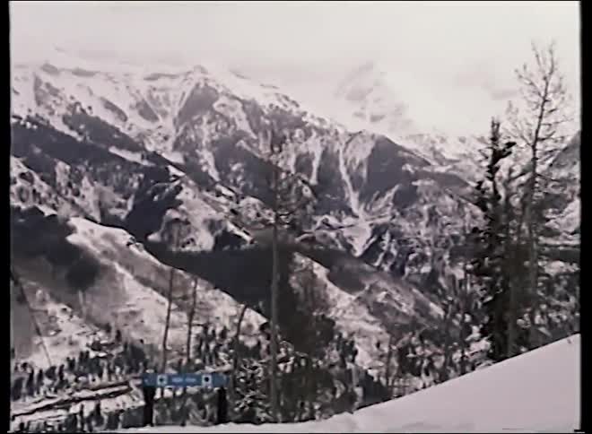 A panning shot reveals a beautiful, snow-covered mountain range at a ski resort in the winter