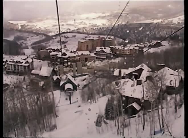Vintage point-of-view shot from a gondola moving over a snow-covered mountain ski resort village