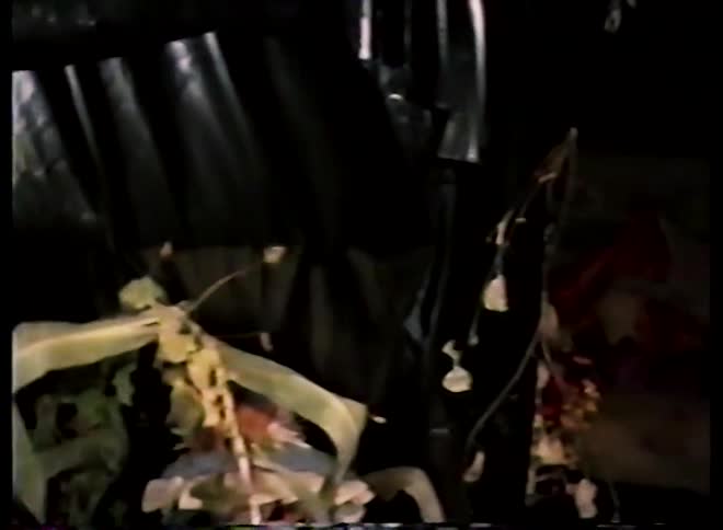 Vintage home video pans from costumed people across a dark and spooky Halloween exhibit with scarecrows and pumpkins