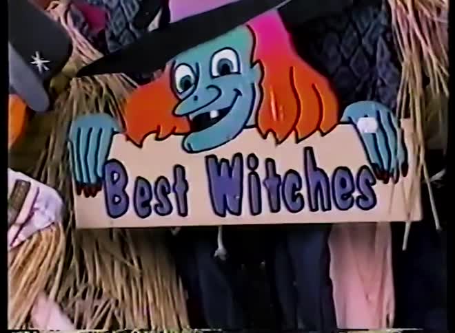 A vintage home video pans across a collection of handmade Halloween decorations including a ghost, witch, and scarecrows