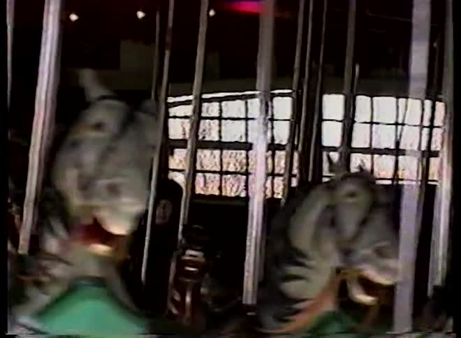 Nostalgic home movie footage from the 1990s shows people enjoying a classic, ornate carousel ride