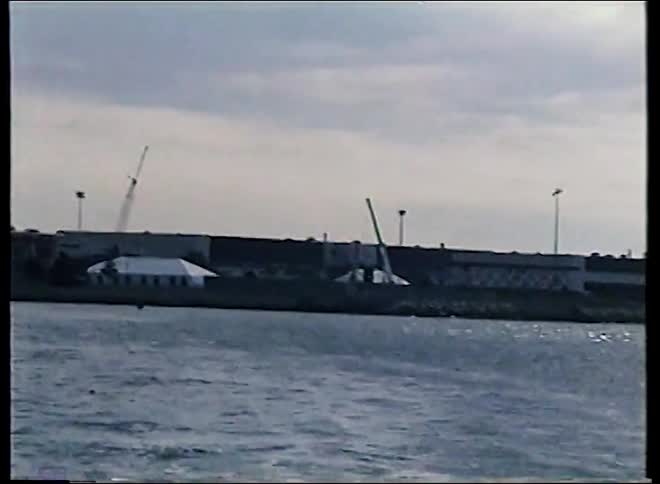 Vintage 1980s footage pans from the Hyatt hotel to airplanes parked at Boston's Logan Airport, as seen from the water