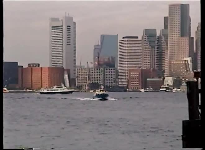 A vintage shot captures boats moving through the Boston Harbor with the iconic city skyline in the background