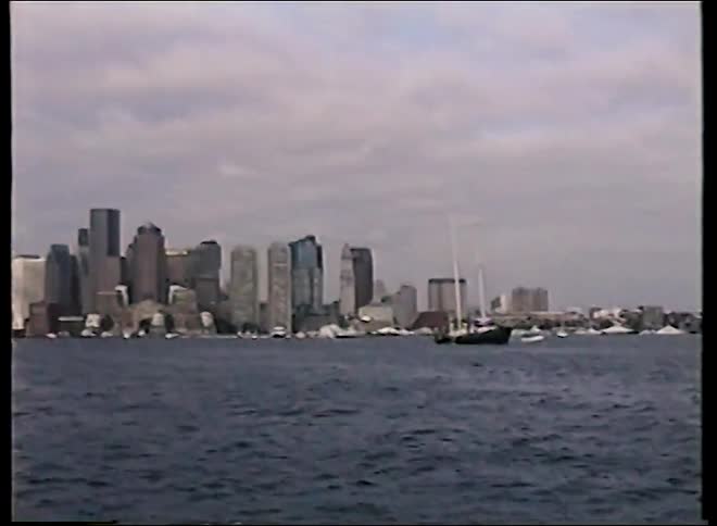 Vintage 1980s footage captures a sailboat on the water in front of the Boston city skyline